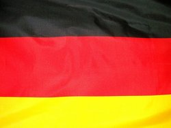 La imagen muestra la bandera alemana desde muy cerca. Se aprecian los colores negro, rojo y dorado típicos de Alemania.