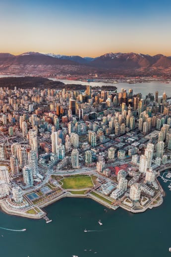 Luchtfoto van het centrum van Vancouver, Canada, met omliggende bergen, havens en bruggen bij zonsondergang.