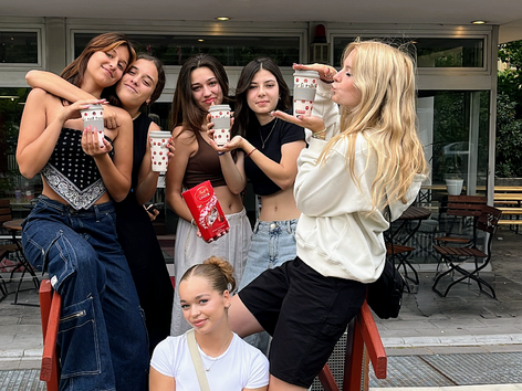 Een groep vrouwelijke studenten poseert met een drankje buiten een Sprachcaffe taalschool.