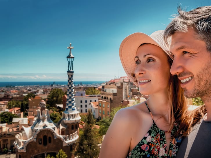 Lachend stel geniet van het uitzicht vanaf Park Güell in Barcelona, Spanje, met de stad en de zee op de achtergrond.