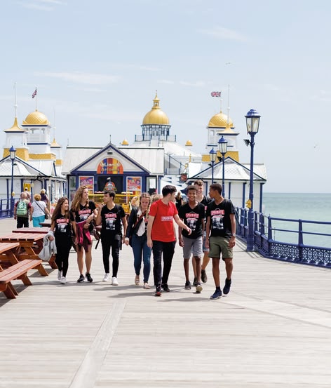 Studenten van Sprachcaffe wandelen langs de pier van Eastbourne bij de zee.