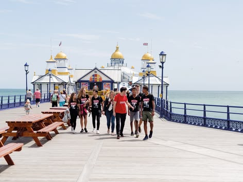 Sprachcaffe students walking along Eastbourne pier by the sea.
