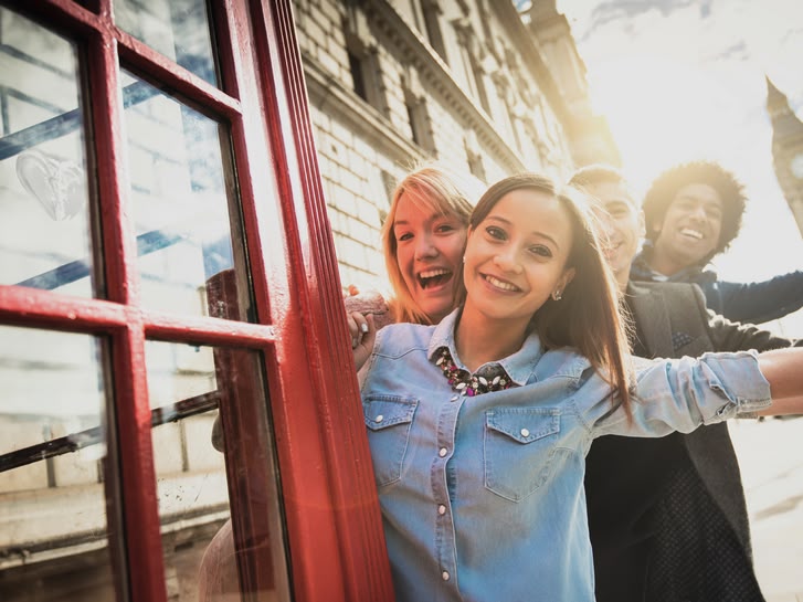 Lachend meisje poseert bij een rode telefooncel in Londen met de Big Ben op de achtergrond.