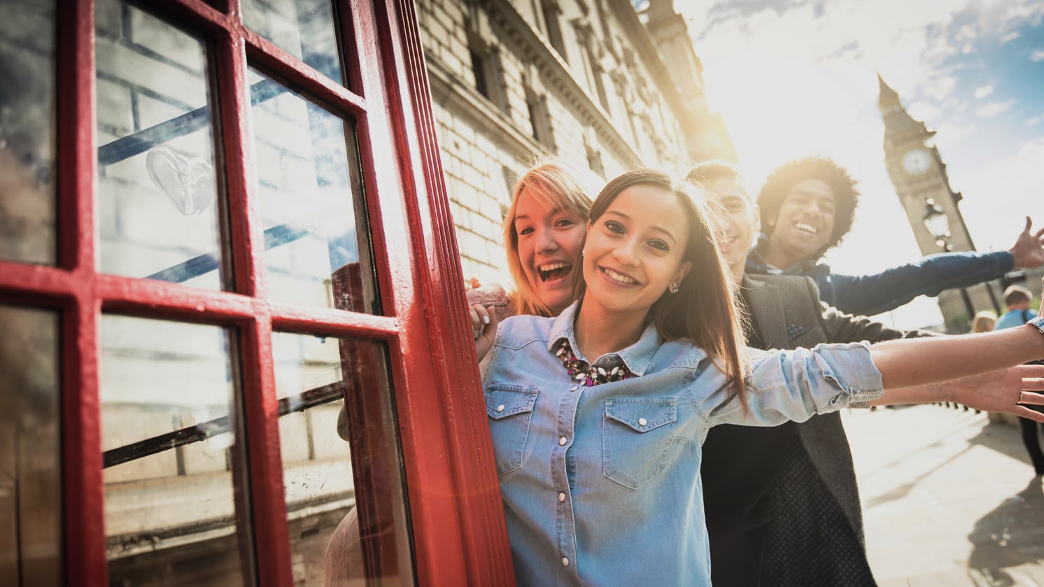 Lachend meisje poseert bij een rode telefooncel in Londen met de Big Ben op de achtergrond.