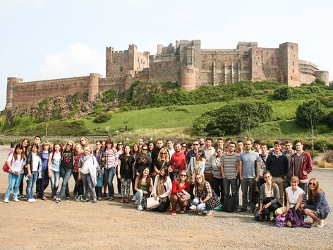 Grote studentengroep voor een historisch Engels kasteel tijdens een Sprachcaffe reis.
