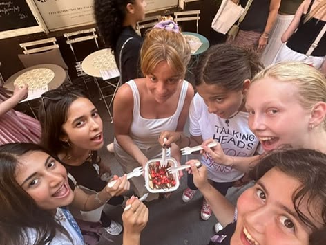 Groep lachende meisjes delen een dessert op straat in Nice, Frankrijk, voor een café.