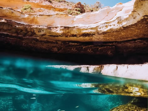 Tiener springt in een natuurlijk zwembad vanaf een rotsachtige klif.